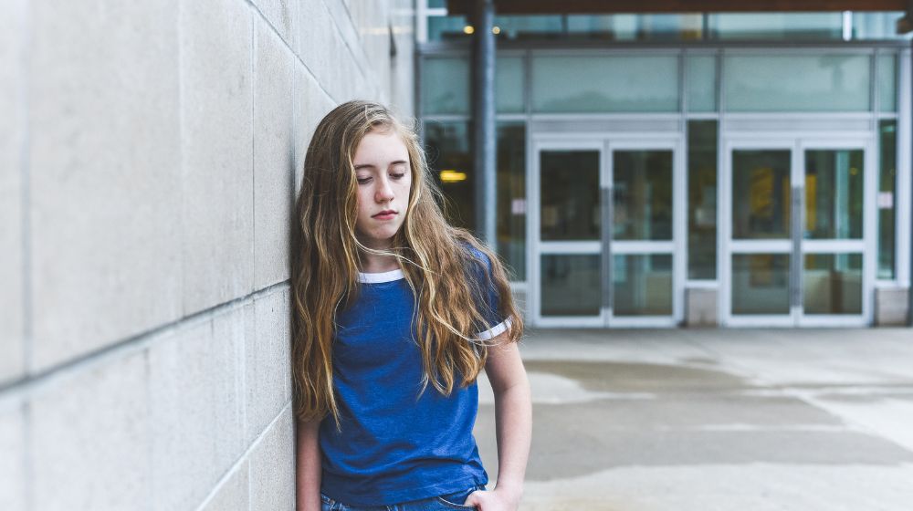 girl leaning on wall looking sad